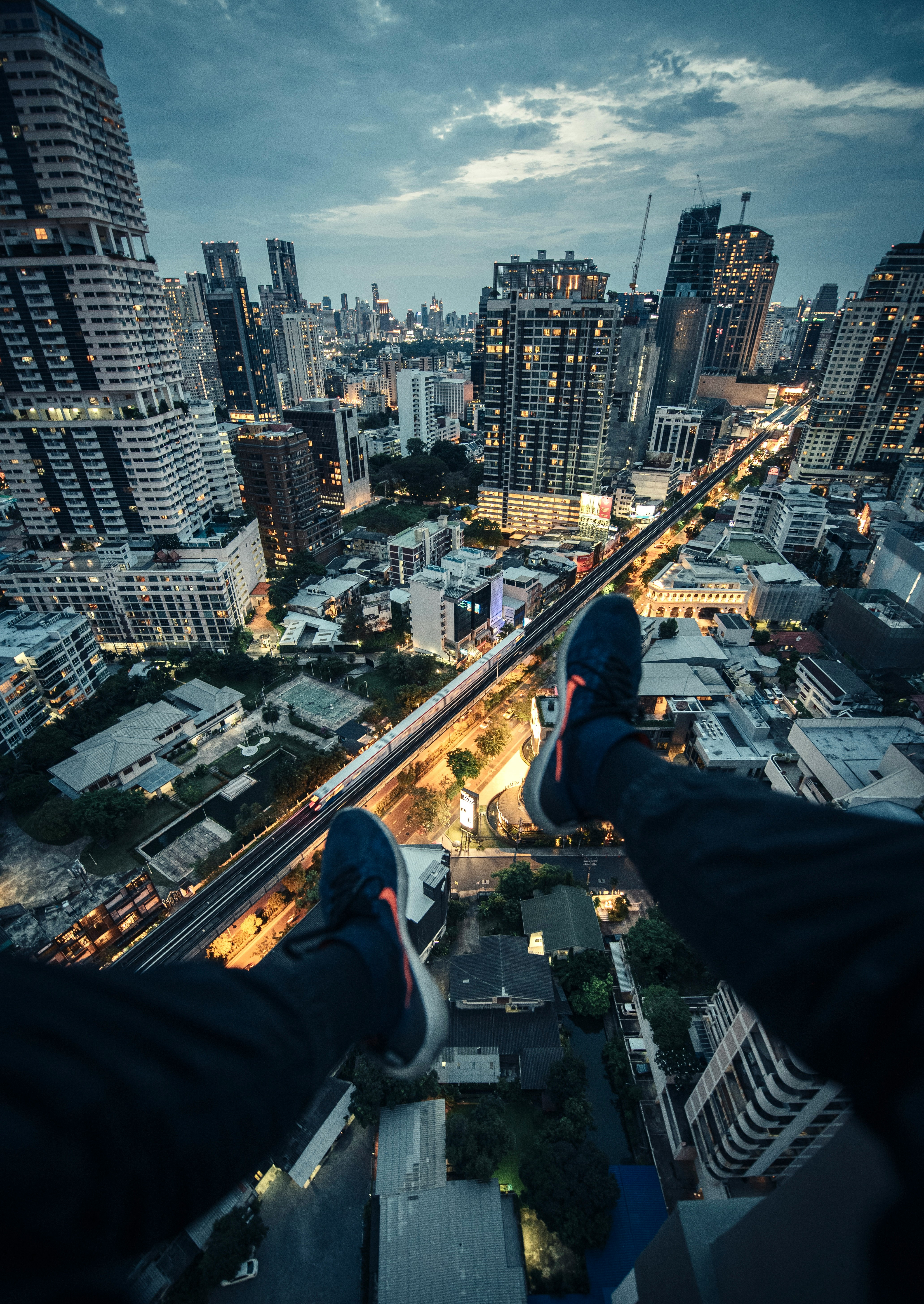 person in black pants and black sneakers sitting on top of building during daytime